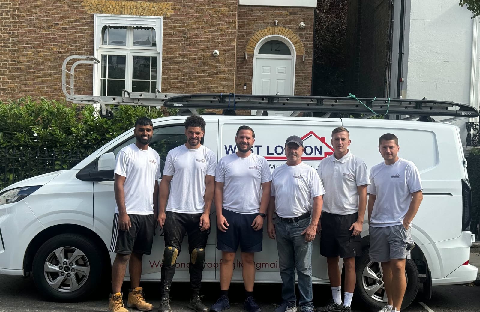 The West London Roofing Maintenance team, six of them in company t-shirts, standing in front of a sign-written van with ladders on the roof