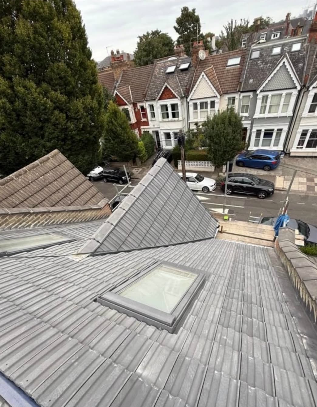 New grey tiled roof with two rooflights fitted, overlooking a street of Victorian terraced houses