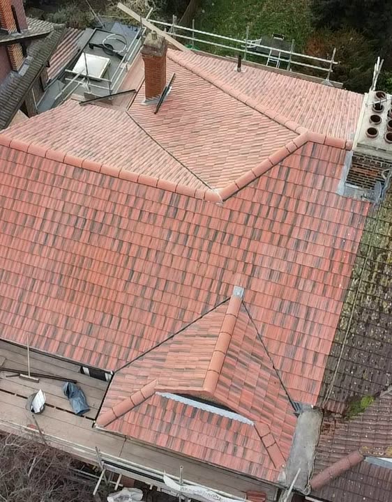 Drone view of a finished roof in new red clay plain tiles with a front gable and two brick chimneys, Hanwell W7