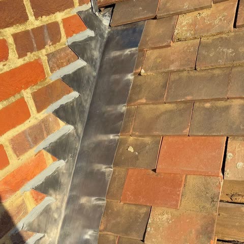 New lead step flashing pointed into brickwork, with the cover flashing dressed over plain tiles
