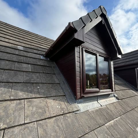 Dormer window with new woodgrain cladding, guttering and lead cheeks on a tiled roof