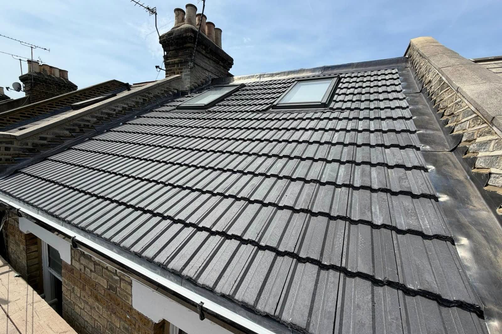 New grey interlocking tile roof with two Velux windows, new lead flashing and a white gutter