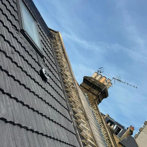 Tiled roof slope with new lead flashing along the parapet and a chimney beyond