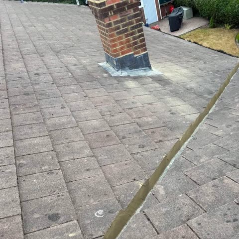 Hip and ridge tiles freshly repointed on a concrete tile roof, the chimney flashed in lead